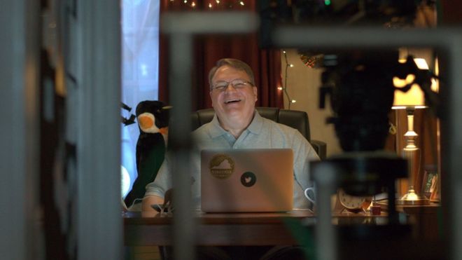 Фотография человека по имени Джон Льюис, улыбающегося его ноутбуку