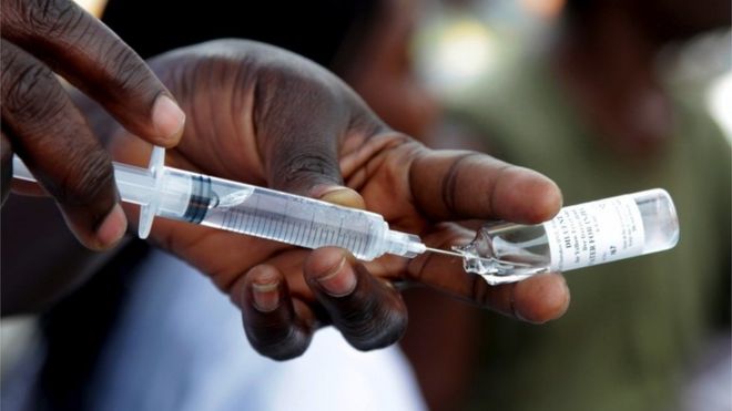 A person draws vaccine out of a bottle with a syringe