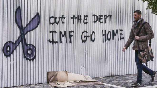 Гражданин проходит мимо граффити против МВФ 10 февраля 2015 года в Афинах, Греция