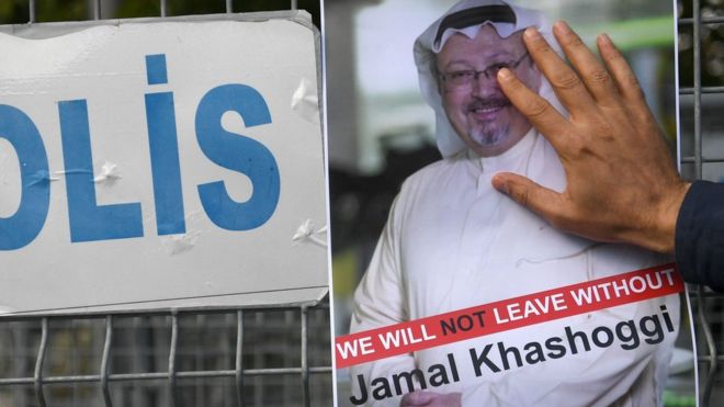 A man puts his hand over a poster of Jamal Khashoggi