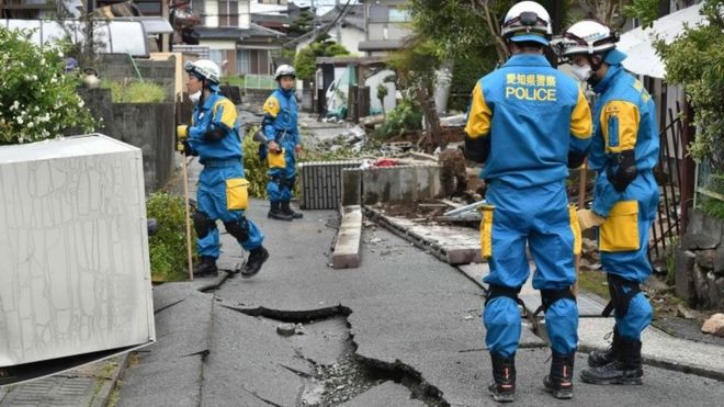 Полицейские разыскивают пропавших людей в поврежденном районе после двух землетрясений в районе Машики, префектура Кумамото (17 апреля 2016 года)
