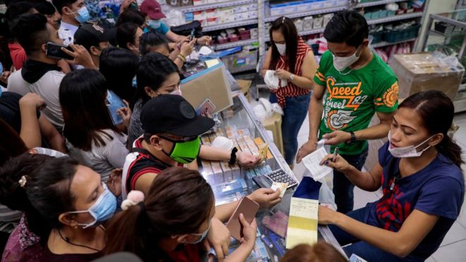 Люди покупают маски для лица в аптеке в Маниле