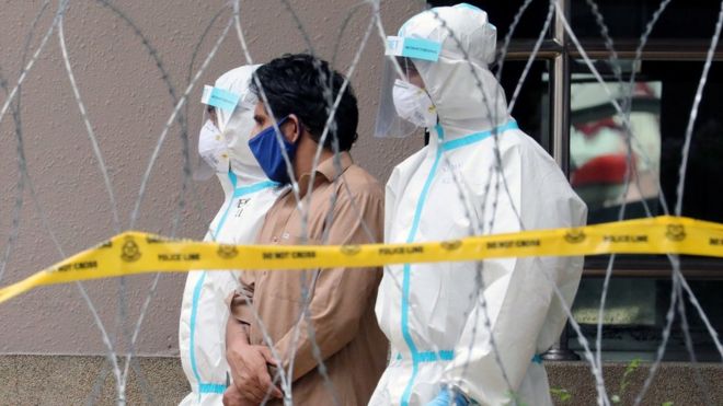 Police officers wearing protective suits a man from an apartment under enhanced lockdown in Kuala Lumpur (1 May 2020)