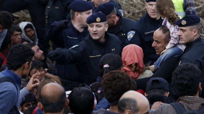 セルビアとの国境で移民に指示するクロアチア警官（18日）