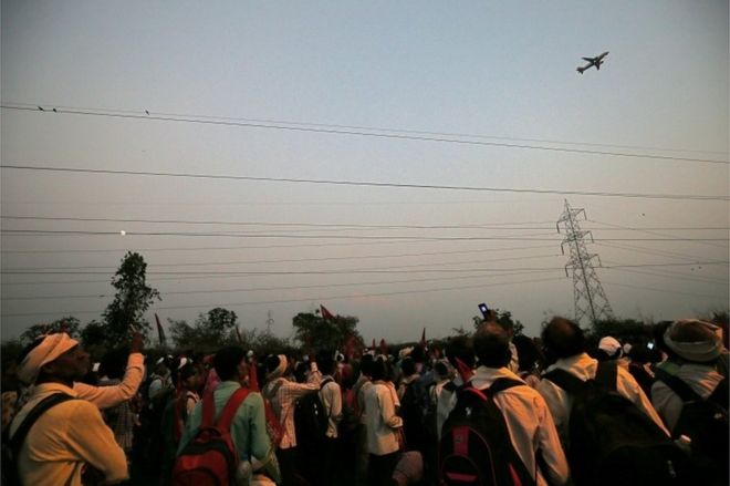 Фермеры используют свои мобильные телефоны, чтобы сфотографировать самолет, когда они маршируют во время акции протеста с требованием лучшей цены на свою продукцию и полного отказа от сельскохозяйственных кредитов, в Мумбаи, Индия, 21 ноября 2018 года.