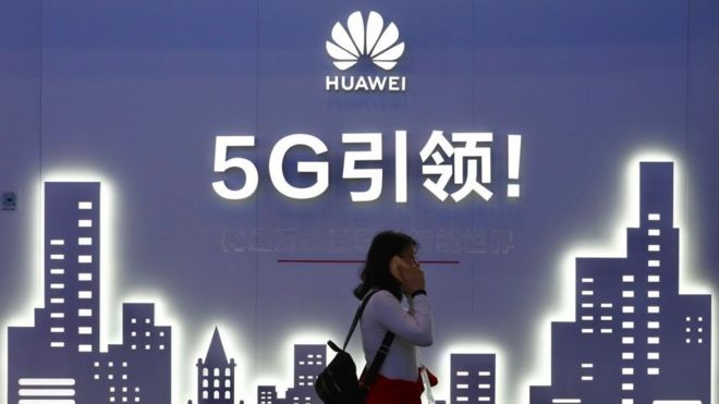 Женщина проходит мимо вывески Huawei 5G в день открытия выставки PT Expo China 2019 в Китайском национальном конференц-центре 31 октября 2019 года в Пекине, Китай.
