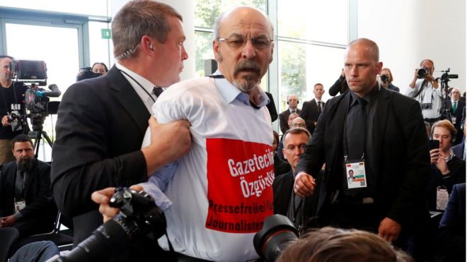 Турецкий журналист Эртугрул Йигит из Avrupa Postasi удален охранниками во время пресс-конференции в Берлине, 28 сентября 2018 года