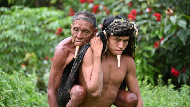 Indígena carga a su padre para recibir vacuna contra covid-19.