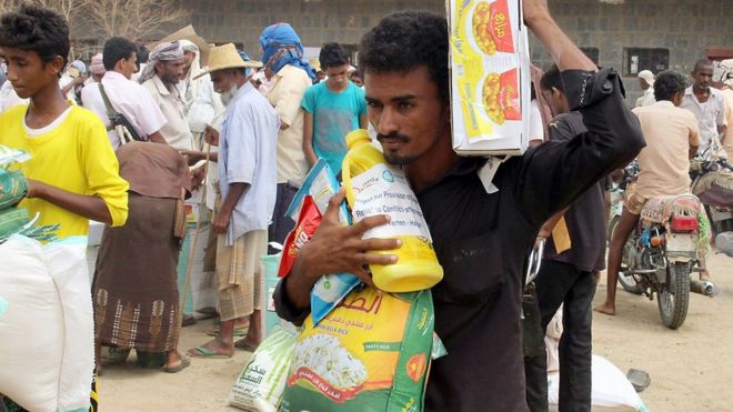 يمنيون يتلقون مساعدات غذائية