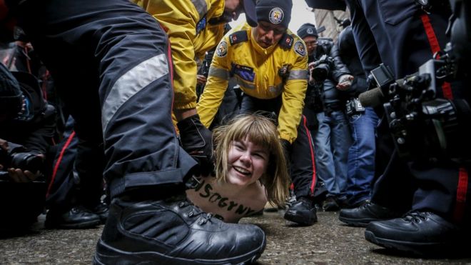 Протестующий без рубашки задержан полицией после того, как судья из Онтарио признал бывшего канадского радиоведущего Цзян Гомеши невиновным по четырем обвинениям в сексуальном посягательстве и подсчету удушья, в Торонто, 24 марта 2016 г.