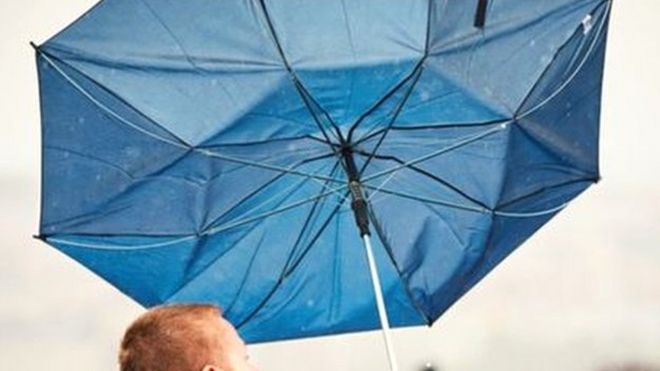 Мужчина держит зонтик, пойманный ветром