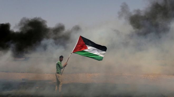 A demonstrator holds a Palestinian flag during clashes in the Gaza Strip in 2018