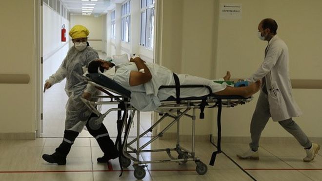 Profissionais de sade transportam paciente em maca de hospital
