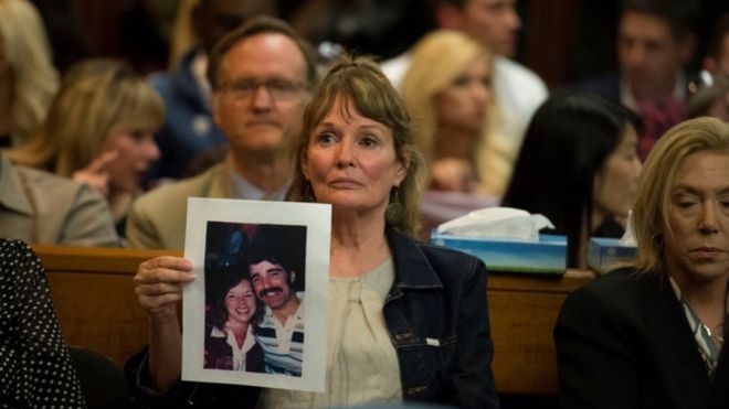 Мелани Барбо держит фотографию жертв Голден Стэйт Киллер в зале суда