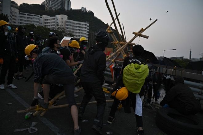 Одетые в черное протестующие пытаются использовать катапульту, сделанную из бамбука, в Китайском университете Гонконга 13 ноября 2019 года.