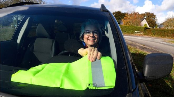 13 ноября 2018 года Жаклин Муро позирует в своей машине, надевая желтый жилет на приборной панели в Бохале, западная Франция