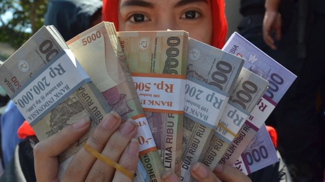 An Indonesian woman holds rupiah notes in 2016