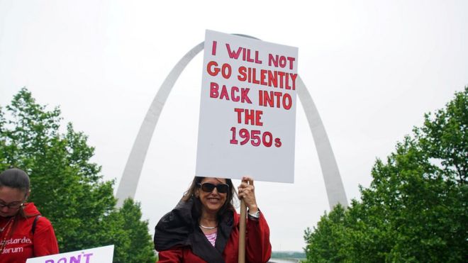 Женщина держит в руках знак протеста, когда сотни женщин протестуют на ступеньках Старого здания суда во время празднования Дня действий против запрета абортов в Сент-Луисе, штат Миссури