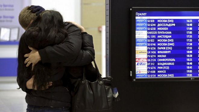 Пара обнимает друг друга возле табло информации о рейсе в аэропорту Пулково в Санкт-Петербурге, Россия (31 октября 2015 г.)