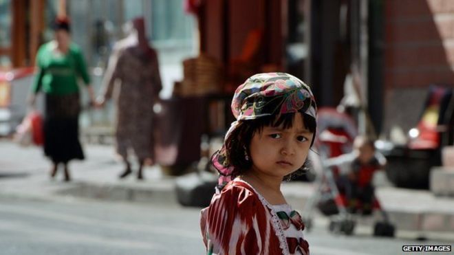 A young Uighur girl waits near the main bazaar in the Muslim quarter of Urumqi, Xinjiang Province on 29 June, 2013
