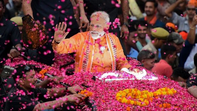 Indian Prime Minister and leader of the Bharatiya Janata Party (BJP) Narendra Modi gestures during a roadshow in Varanasi on April 25, 2019