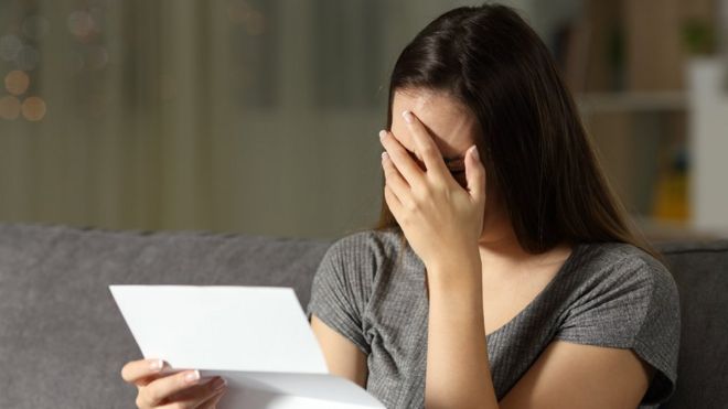 Sad woman reading a letter in the dark