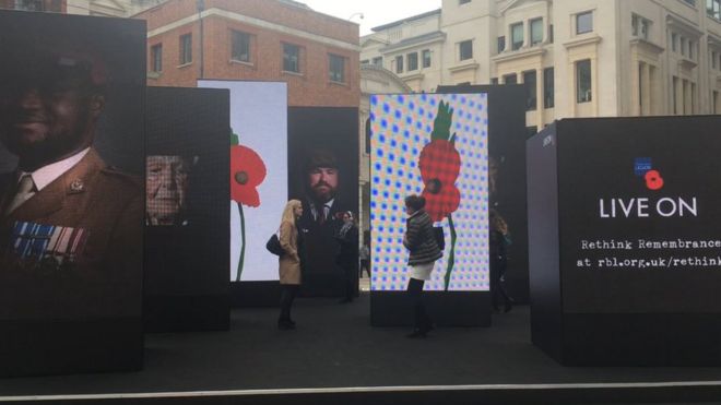 Люди гуляют по видеоинсталляции Королевского британского легиона "Переосмыслить" в Лондоне.