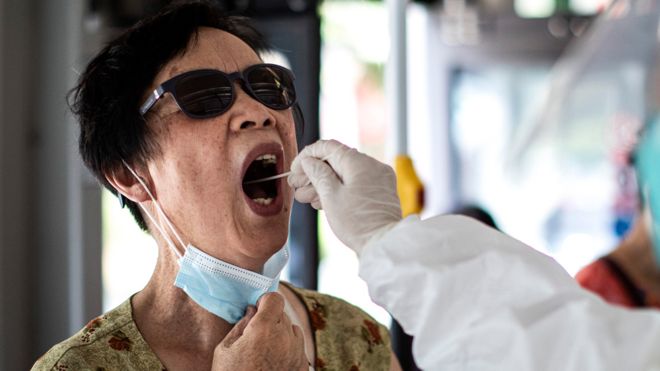 A medical worker takes samples during a mass Covid-19 test in a residential block on August 3, 2021 in Wuhan