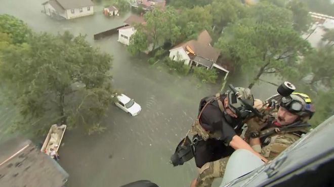 Двое спасателей из Морской вертолетной эскадрильи ВМС США 7 спущены в дом после того, как тропический шторм Харви затопил район в Бомонте, штат Техас, 30 августа