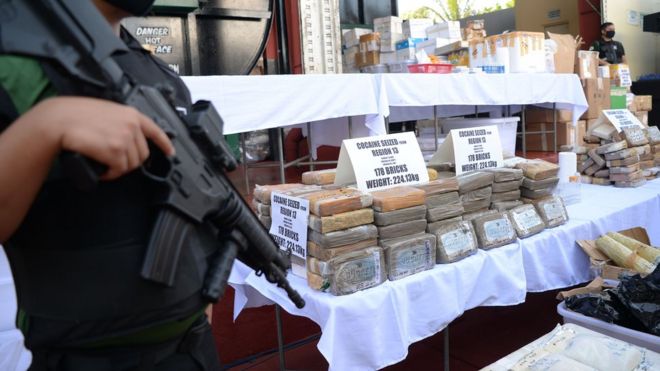 Вооруженные агенты Филиппинского агентства по борьбе с наркотиками (PDEA) стоят на страже возле изъятых запрещенных наркотиков, включая брикеты кокаина