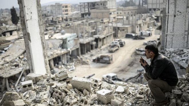 28 января 2015 года курдский мужчина разговаривает по радио, проверяя восточную часть сирийского пограничного города Кобане, известного как Айн-эль-Араб.