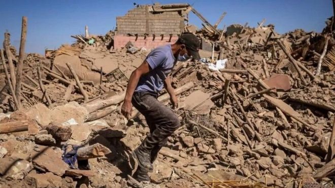 Un homme marche dans les décombres d'un village en ruine