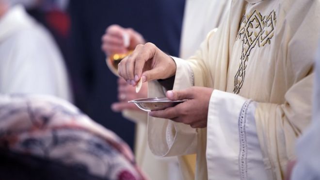 Padre segura hóstia