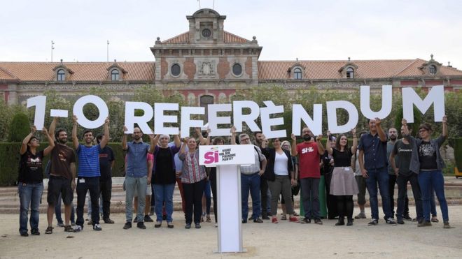 Члены каталонского движения за независимость держат плакат, на котором упоминается голосование референдума 1 октября