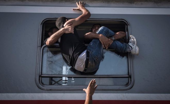 Мигрант пытается войти в поезд через окно
