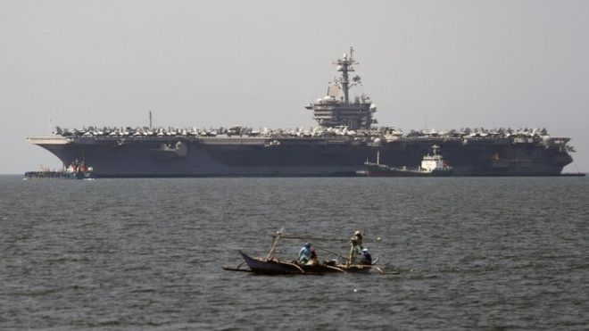 Filipino fishermen in a boat manoeuvre next to the US aircraft carrier "USS Carl Vinson" at the Manila Bay, Philippines, 17 February 2018.