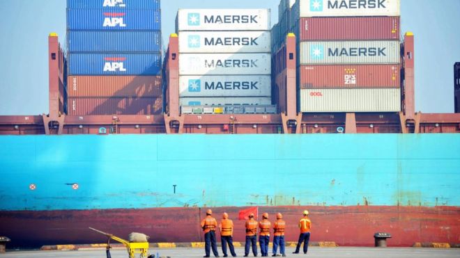 Китайские рабочие выглядят как грузовой корабль, загруженный в порту в Циндао, провинция Шаньдун на востоке Китая, 13 июля 2017 года.