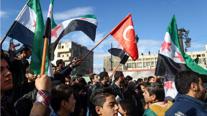 Syrians wave Turkish and Syrian-rebel flags as they demonstrate in the rebel-held town of Azaz in northern Syria on January 19, 2018, in support of a joint rebel and Turkish military operation against Syrian-Kurdish forces in Afrin.