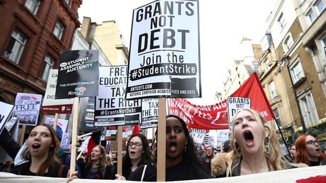 Демонстранты маршируют во время демонстрации против студенческих сборов в Лондоне в ноябре 2015 года