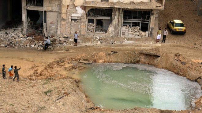 Жители удерживаемого повстанцами района Тарик аль-Баб осматривают заполненный водой кратер, который, по словам активистов, был вызван взрывом бомбы (23 сентября 2016 года)