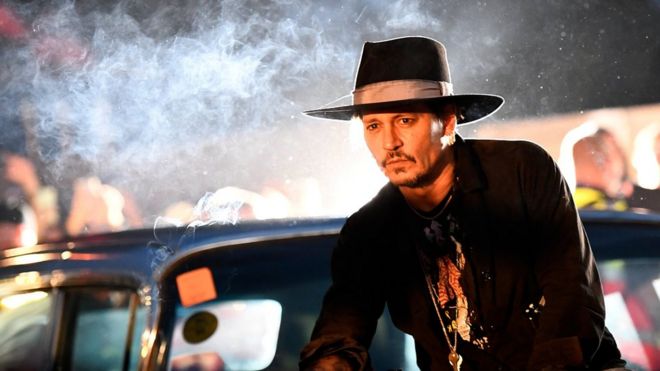 Johnny Depp poses on a Cadillac during the Glastonbury Festival