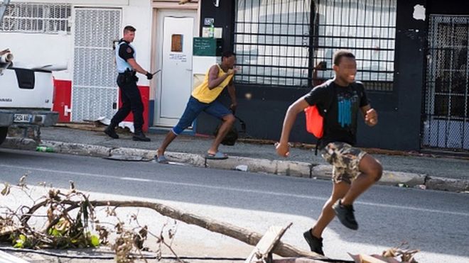 Солдат французской жандармерии преследует предполагаемых мародеров, когда они бегут мимо разрушительного урагана Ирма на острове Святого Мартина (8 сентября 2017 года)