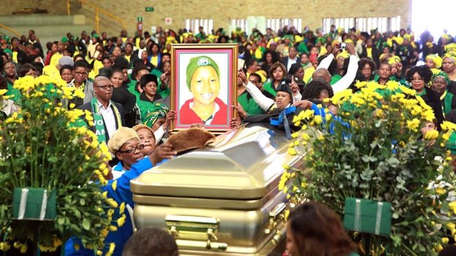 Родственники, партийные активисты и представители Женской лиги АНК делают жест рядом с гробом и портретом кандидата в опеку покойного Африканского национального конгресса (АНК) Ханисиле Нгобес-Сибиси,