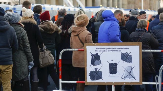 Посетители ждут, чтобы пройти проверку безопасности на ярмарочной площадке перед предстоящим празднованием Нового года, недалеко от Бранденбургских ворот в Берлине, Германия, 30 декабря 2015 года.