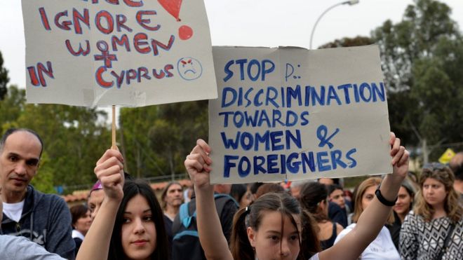Протестующие держат плакаты, призывающие положить конец дискриминации женщин и иностранцев на Кипре