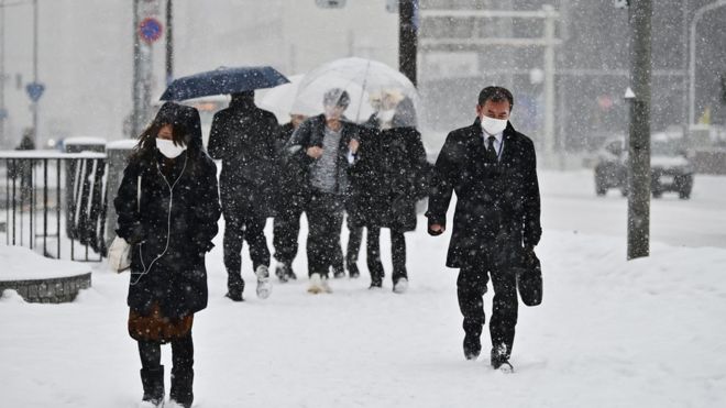 Люди на Хоккайдо ходят в масках сквозь снегопад (февраль 2020 г.)