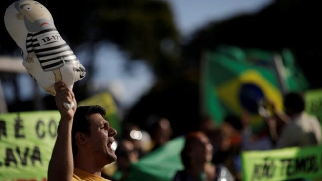 Люди протестуют против бывшего президента Бразилии Луиса Инасиу Лула да Силва, прежде чем бразильский суд примет решение по апелляции Лула да Силва против обвинения в коррупции, которая может помешать ему участвовать в президентской гонке 2018 года в Бразилиа, Бразилия, 23 января 2018 года | || Фернандо Холидей, 21 год, говорит, что MBL меняет взгляды на право в Бразилии