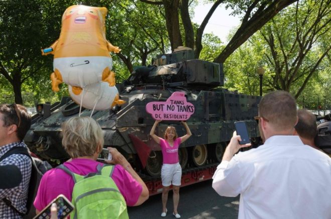Протестующий стоит рядом с танком