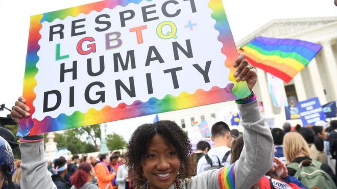 Una joven con una pancarta que pide respeto para la dignidad humana de la comunidad LGBTQ