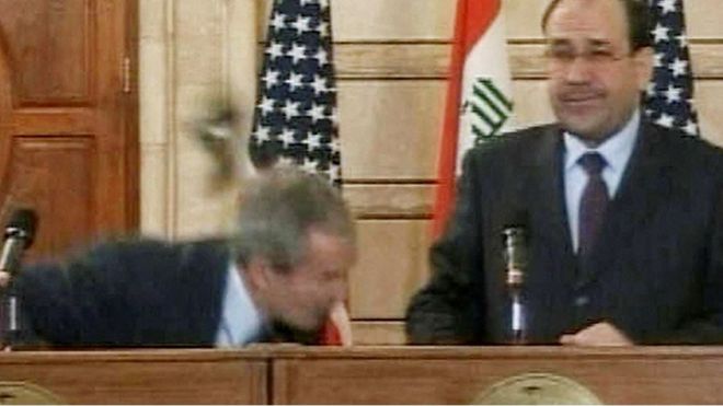 美国前总统小布什试图躲避伊拉克记者扔过来的鞋子的画面